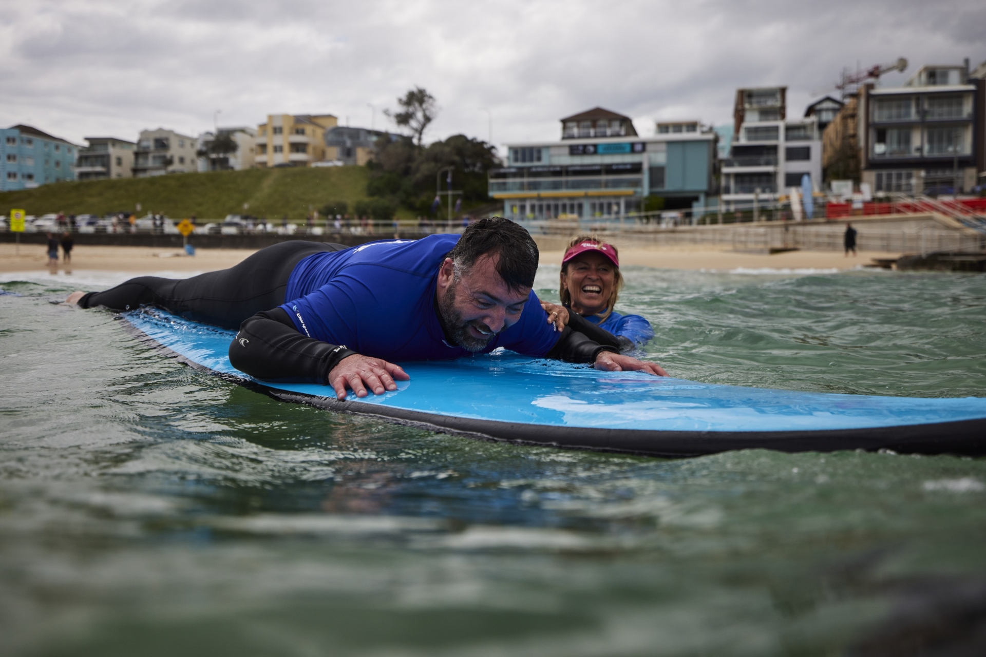 新南威尔士州，邦迪海滩，一名视力不佳的男子在”海滩冲浪之旅“教练的指导下冲浪 © 澳大利亚旅游局版权所有