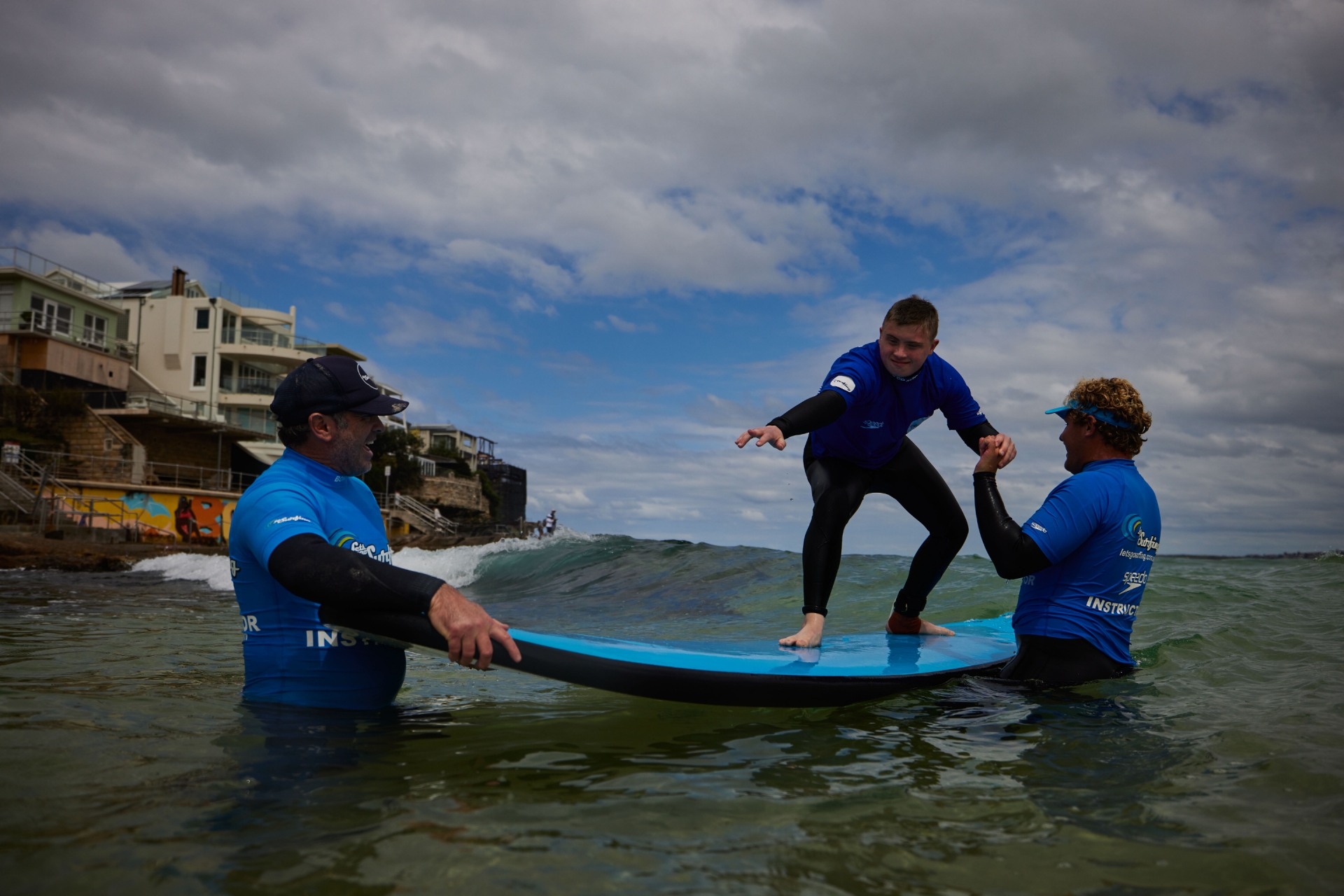 新南威尔士州，悉尼，邦迪海滩，一名患有神经分化症的男子在”海滩冲浪之旅“教练的指导下冲浪 © 澳大利亚旅游局版权所有