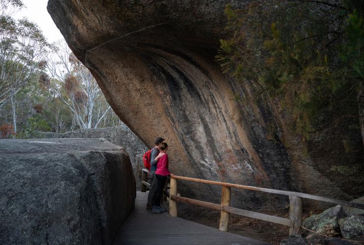 澳大利亚首都领地，堪培拉，纳玛吉国家公园，在 Yankee Hat 观看岩画的情侣 © 澳大利亚旅游局，Rob Mulally 版权所有
