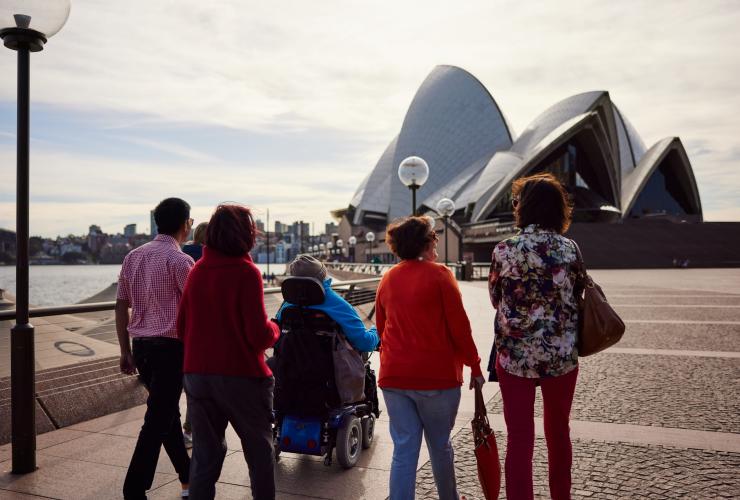 新南威尔士州，悉尼，澳大利亚风尚旅行社，一位坐轮椅的男子与其家人一起走近悉尼歌剧院 © 新南威尔士州旅游局版权所有