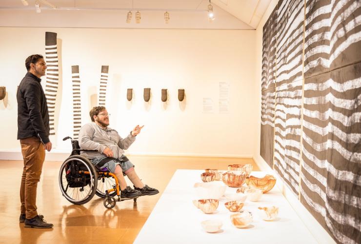 北领地，爱丽斯泉，一位坐轮椅的男子在阿拉伦艺术中心欣赏艺术作品 © 北领地旅游局/Helen Orr 版权所有