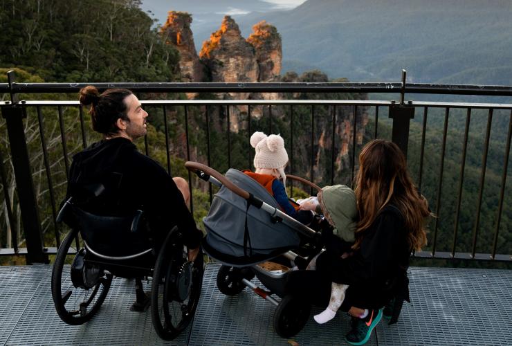 新南威尔士州，蓝山，一位坐轮椅的男子在三姐妹峰观景点与其家人在一起 © 澳大利亚旅游局版权所有