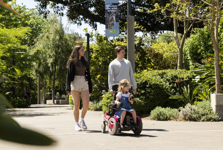 南澳大利亚州，阿德莱德，一位坐轮椅的小女孩与其父母一起在阿德莱德动物园 © 澳大利亚旅游局版权所有