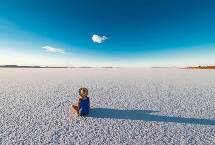 头戴遮阳帽的女子，坐在位于南澳大利亚州的盖尔德纳湖的盐滩上 © 南澳大利亚旅游局版权所有