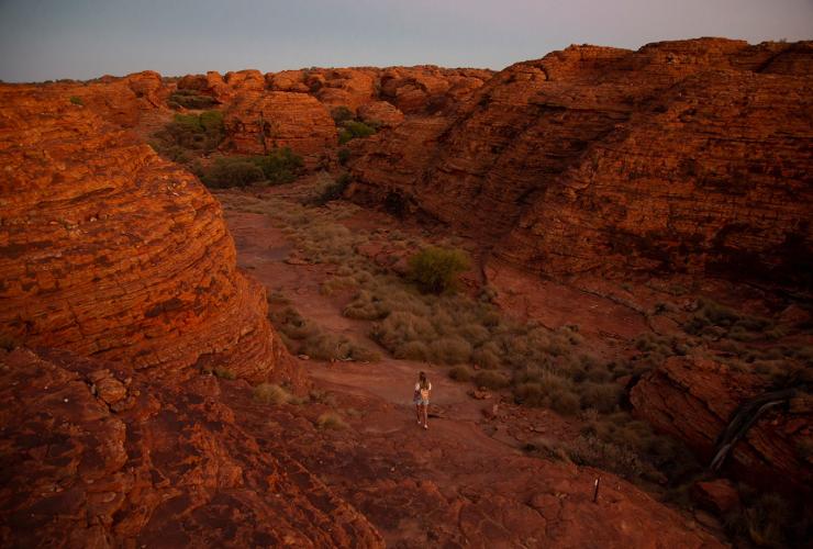北领地，国王峡谷，在国王峡谷边缘步道从岩石间穿过的女性 © 澳大利亚旅游局版权所有