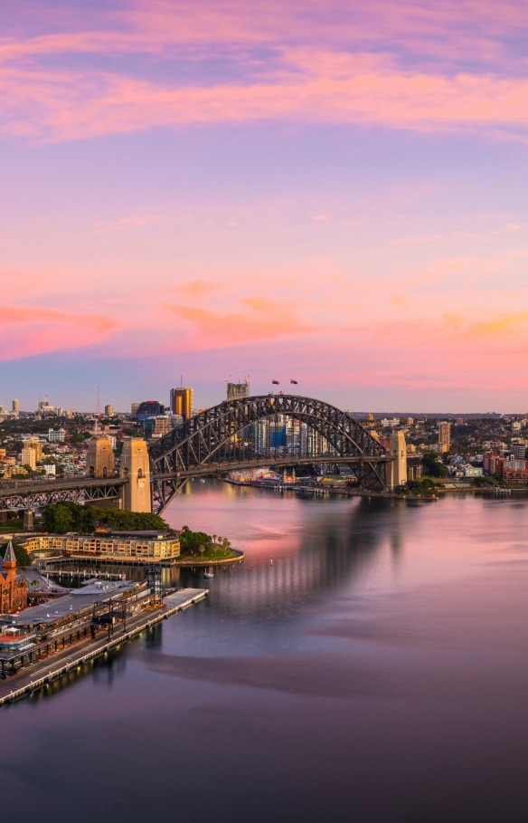 新南威尔士州，悉尼海港鸟瞰图，蓝色的海水与粉色和金色的晚霞相互映照 © 新南威尔士州旅游局版权所有