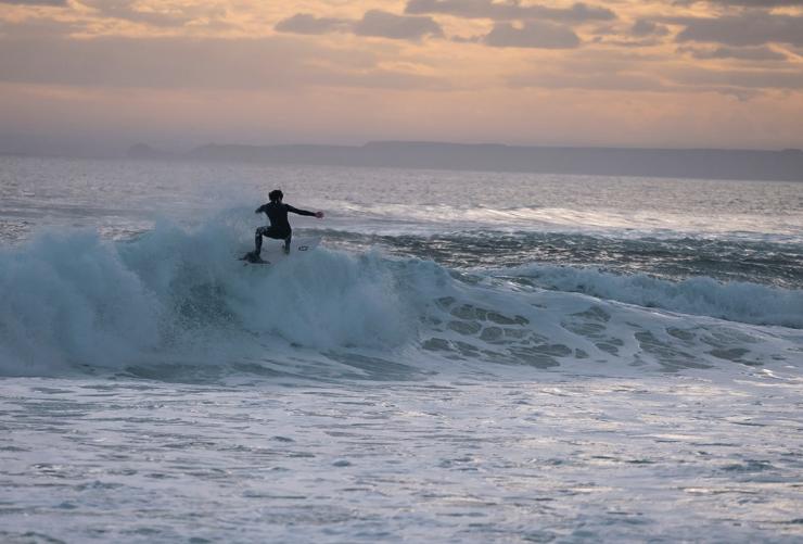 维多利亚州，菲利普岛，在乌拉迈海岬的落日之下，一位冲浪者站在浪尖 © 澳大利亚旅游局版权所有