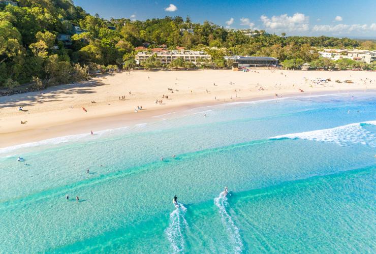 昆士兰州，努沙，俯瞰碧蓝色的海水和淡金色的沙滩旁，冲浪者向努沙主海滩的海岸乘风破浪而来 © 昆士兰州旅游及活动推广局版权所有