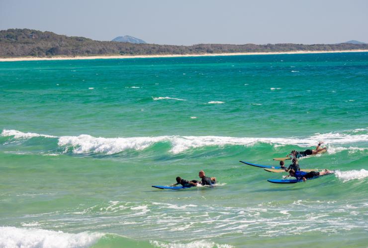 昆士兰州，努沙，在努沙主海滩，几个冲浪者躺在冲浪板上，身后洁白如雪的海浪滚滚而来 © 澳大利亚旅游局版权所有