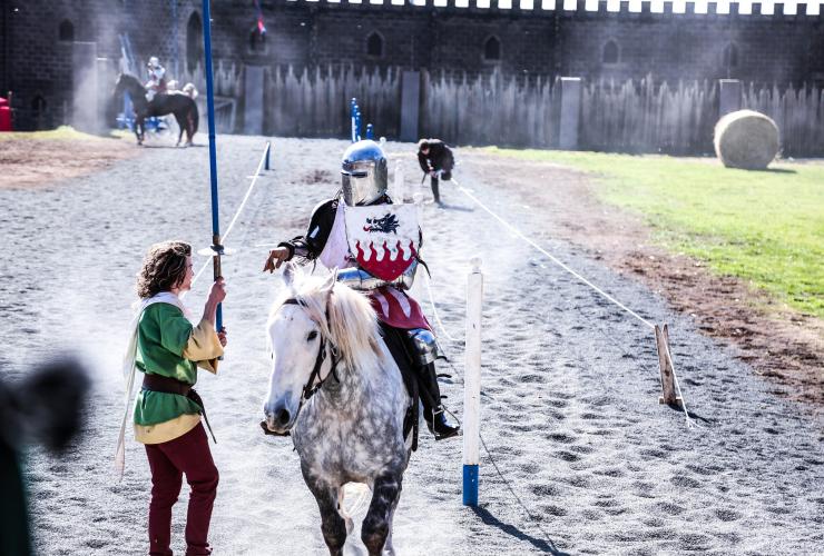 维多利亚州，巴拉瑞特，在克里尔城堡，一个骑士装扮的人骑着马，另一个穿着中世纪服饰的人递给他一把剑 © 克里尔城堡版权所有