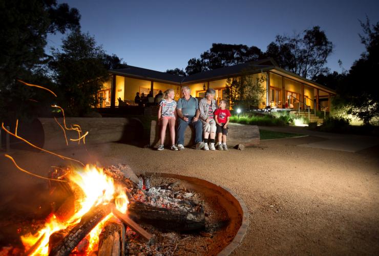 新南威尔士州，达博，塔龙加西部平原动物园，夜幕下一家人围坐在动物园游猎旅舍和比拉邦营地的篝火旁 © 塔龙加版权所有