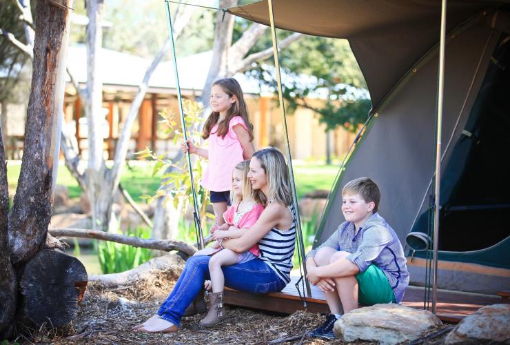 新南威尔士州，达博，塔龙加西部平原动物园，一家人坐在帐篷外，眺望动物园游猎旅舍和比拉邦营地的荒野风光 © 塔龙加版权所有