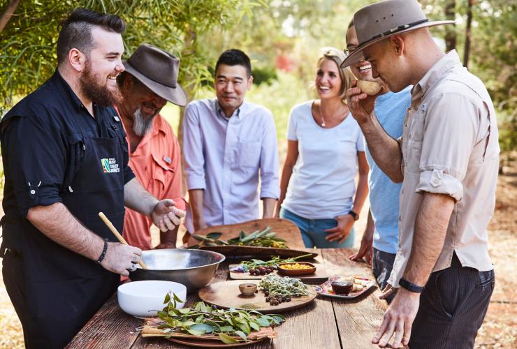 北领地,尤拉拉,丛林美食体验之旅,一群人围在一桌丛林美食旁 © 原住民旅行度假集团版权所有