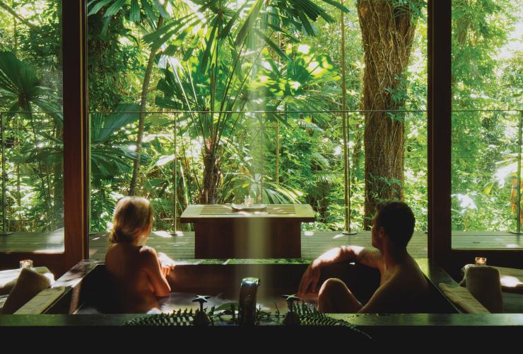 昆士兰州，一对夫妇在道格拉斯港的希尔奇橡树酒店里泡澡，欣赏窗外的戴恩树热带雨林 © 希尔奇橡树酒店版权所有